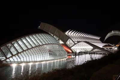 Illuminated modern architecture at night with water reflections.