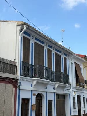A row of traditional white buildings with blue accents and wrought iron balconies under a clear sky.
