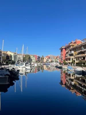A tranquil marina with colorful buildings and boats under a clear blue sky.