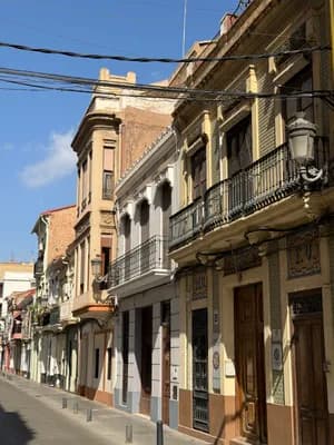 A street lined with ornate buildings featuring balconies and street lamps under a clear blue sky.