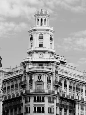 A black and white image of a tall, ornate building with a curved facade and multiple balconies.