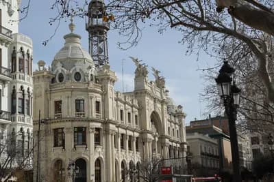 Historic building with ornate architecture and bare tree branches in the foreground.
