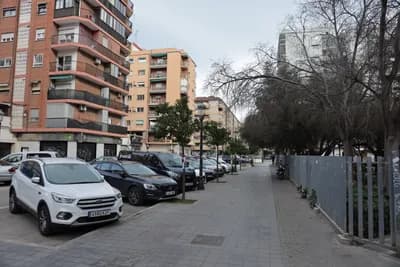 Parked cars along a street with apartment buildings and a sidewalk.