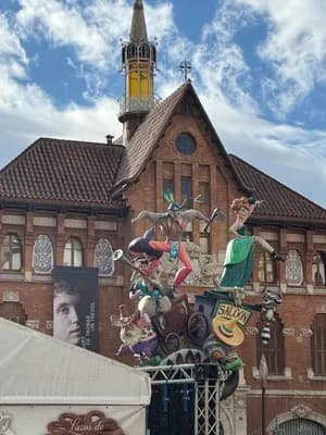 A festive float with figures and a 'Saloon' sign in front of a brick building with a spire.