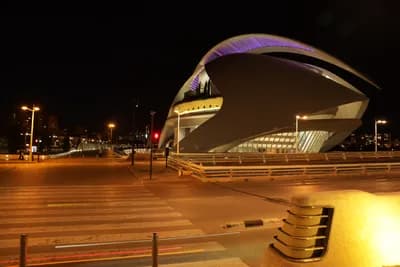 Modern architecture at night with illuminated building and pedestrian crossings.