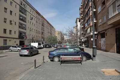 Parked cars and residential buildings along a street.