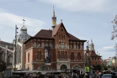 Historic red-brick building with spire in urban setting
