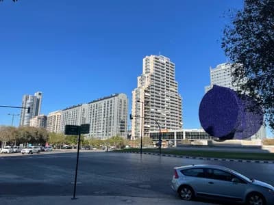 A modern urban scene with a large blue circular sculpture, tall buildings, and a clear blue sky.