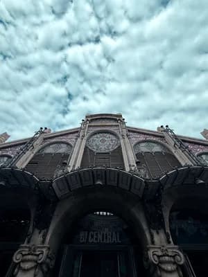 Ornate facade of Mercat Central with a cloudy sky above.