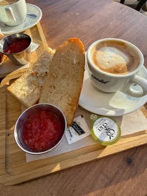 A wooden tray with coffee, toast, jam, and salsa.