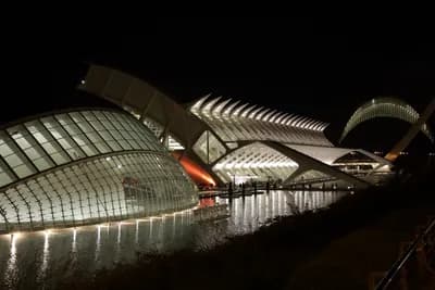 Illuminated modern architecture at night with water reflections.