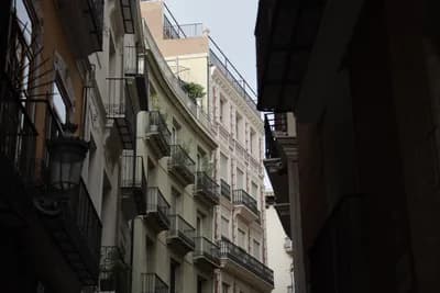 Narrow alleyway with balconies and streetlamp.