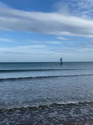 Windsurfer on calm sea under partly cloudy sky