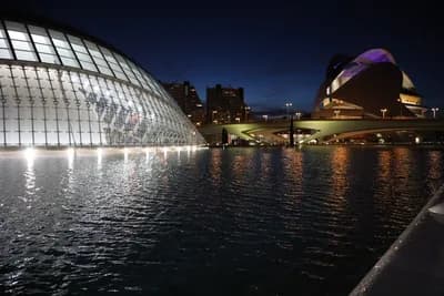 Modern buildings illuminated at night with water reflections.
