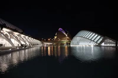 Modern buildings with reflective water surface at night.