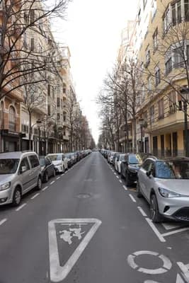 A street scene with parked cars and residential buildings on both sides.