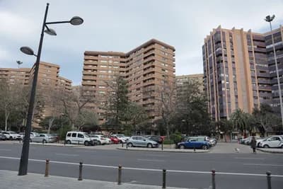 Urban street with parked cars and residential buildings.