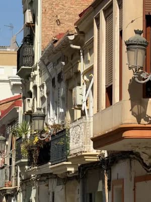 Narrow street with ornate balconies and street lamps in a historic European city.
