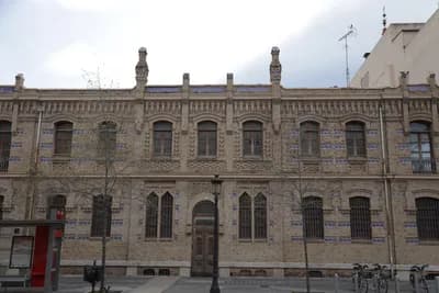 Historic building with arched windows and stonework under a cloudy sky.