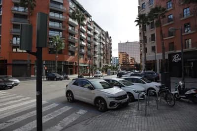 Geparkeerde auto's en woongebouwen langs een straat.