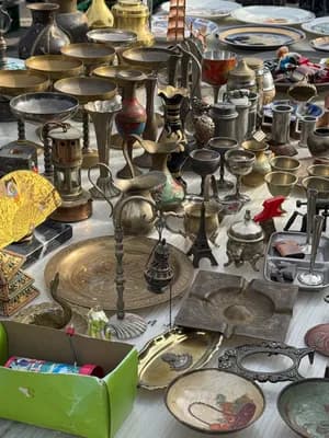 Vintage items on a table: brassware, vases, decorative plates, and ornamental objects.