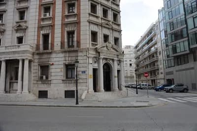 A classical-style building with columns and a central archway at a street corner.