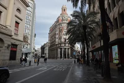 A wide street with palm trees and a historic building in Valencia, Spain.