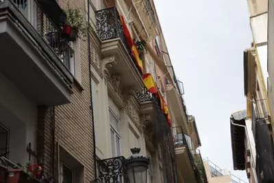 Narrow street with balconies and Spanish flags.