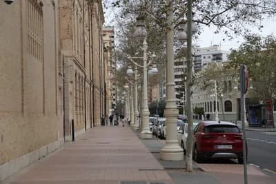 A street scene with white lampposts and a red car parked on the right side.