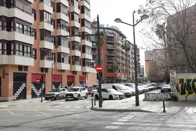 Modern urban street with parked cars and residential buildings.