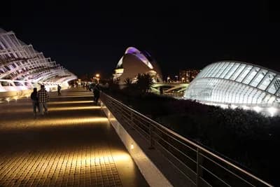 Modern illuminated architecture at night with a pathway and railing.
