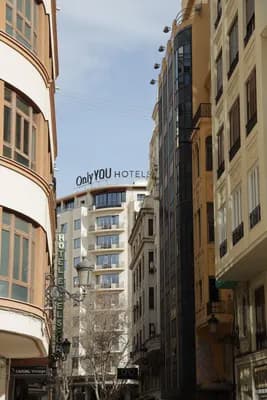 Narrow street with tall buildings and a 'Only YOU HOTELS' sign.