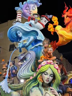 A vibrant float with mermaid and devil figures at night.