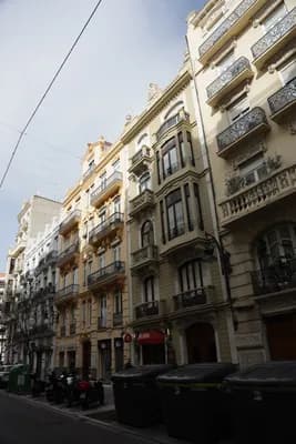 A row of ornate buildings with balconies and windows in a city street.