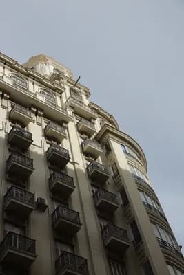 A multi-story building with ornate balconies and a curved facade under a clear sky.