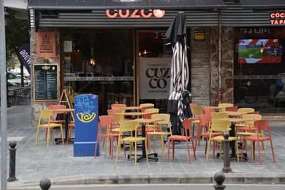 Outdoor seating at a restaurant with colorful chairs and a striped umbrella.
