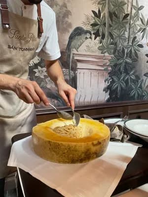 A chef in an apron preparing a melon-based dish with a spoon.