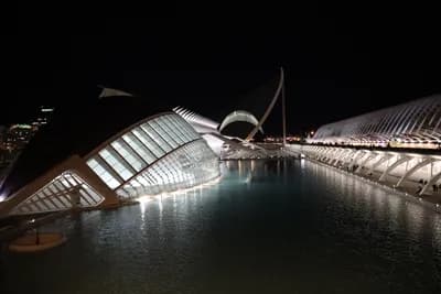 Modern architecture lit up at night with reflections in water.