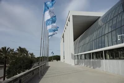 Modern building with glass facade and waving flags.