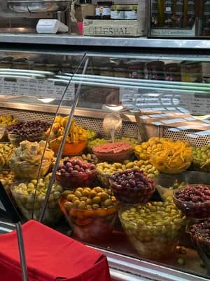A display case filled with different types of olives and pickled items in a market setting.