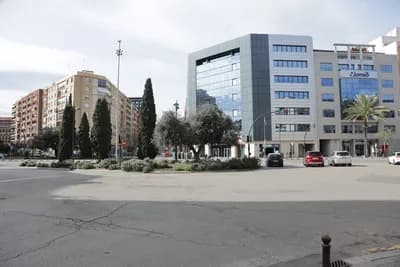 Urban intersection with buildings, trees, and vehicles.