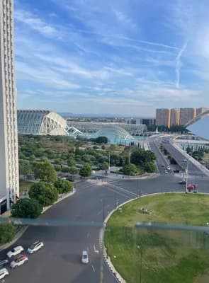 A modern urban landscape with a distinctive building, greenery, and a road network.