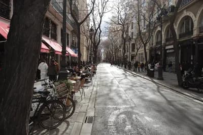 Street scene with bicycles, outdoor dining, and pedestrians.