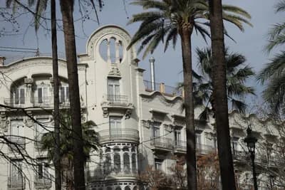A white building with balconies and palm trees.