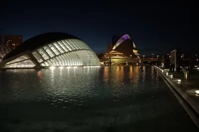 Modern buildings lit up at night with reflections in the water.