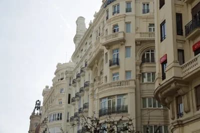 Elegant beige buildings with ornate balconies and windows under a cloudy sky.