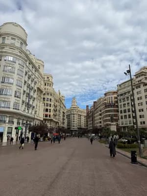 A wide plaza with tall buildings and a cloudy sky.