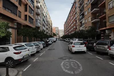 A street scene with parked cars and apartment buildings.