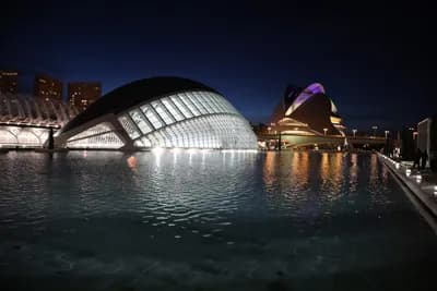 Modern architecture illuminated at night, reflected in water.