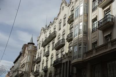 Row of ornate buildings with balconies and intricate architectural details under a cloudy sky.